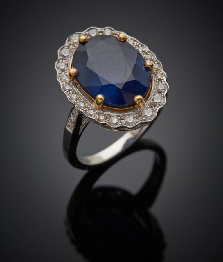 BAGUE "marguerite" en or gris et or jaune (750‰) serti d'un saphir ovale, entou…
