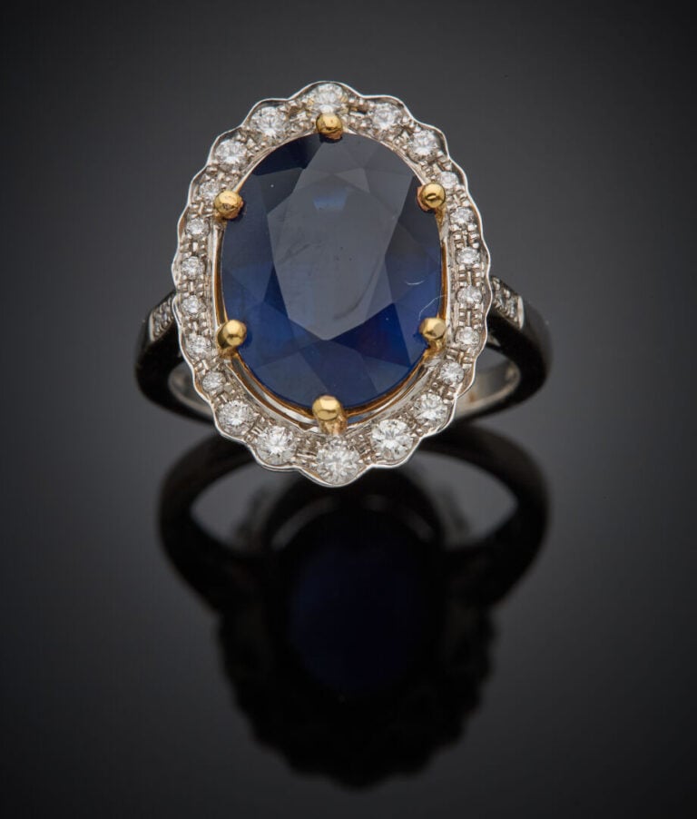 BAGUE "marguerite" en or gris et or jaune (750‰) serti d'un saphir ovale, entou…