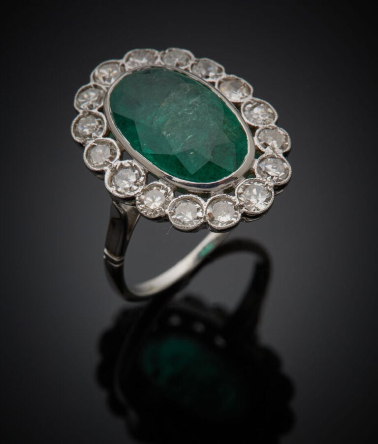 BAGUE "Marguerite" en or gris serti d'une émeraude de forme ovale entourée de d…