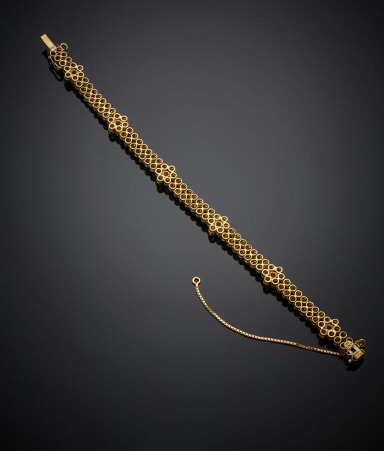 BRACELET articulé en or jaune (750‰) à motifs de pastilles guillochées, flanqué…
