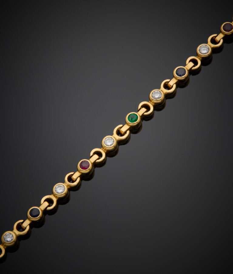 BRACELET articulé en or jaune (750‰) serti d'un alignement de diamants, émeraud…