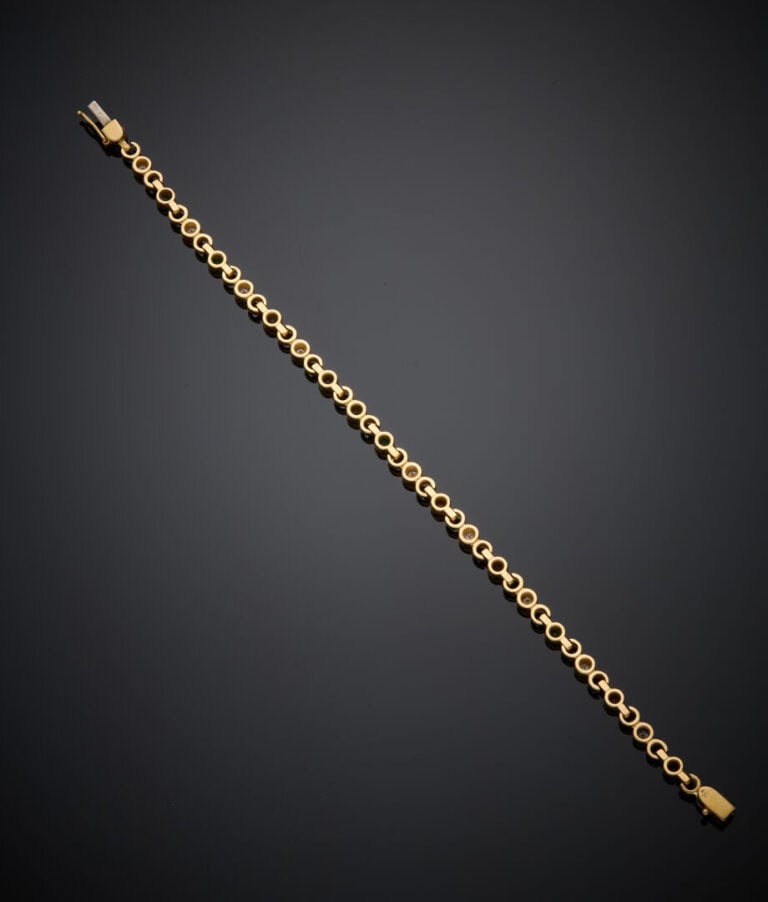 BRACELET articulé en or jaune (750‰) serti d'un alignement de diamants, émeraud…