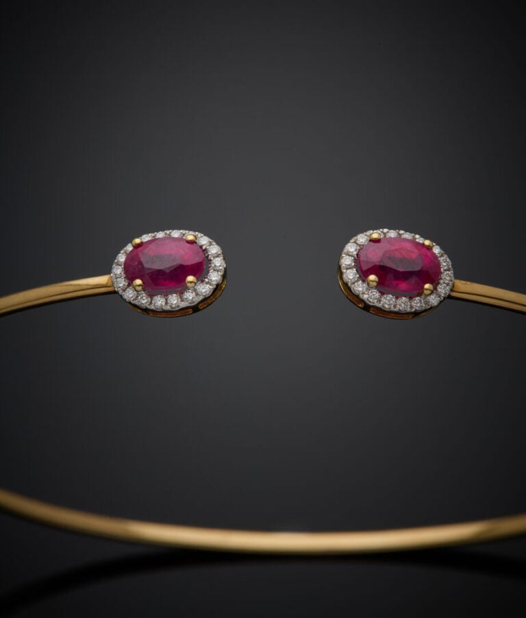 BRACELET fin ouvert en or jaune (750‰) terminé par deux rubis ovales entourés d…