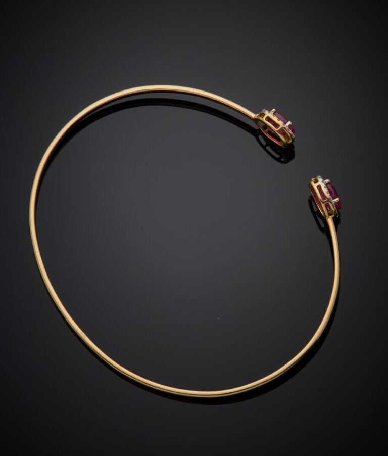 BRACELET fin ouvert en or jaune (750‰) terminé par deux rubis ovales entourés d…