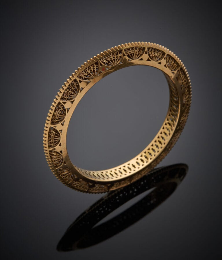 BRACELET rigide en or jaune (750‰) ciselé, cranté et repercé. - - Long.: 17 cm…