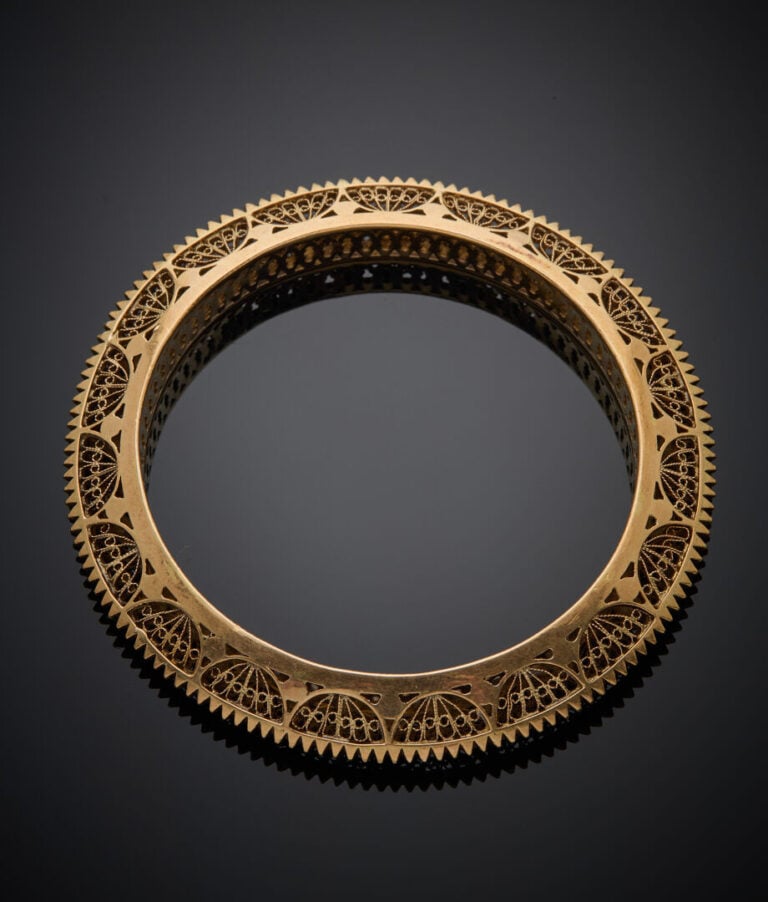 BRACELET rigide en or jaune (750‰) ciselé, cranté et repercé. - - Long.: 17 cm…