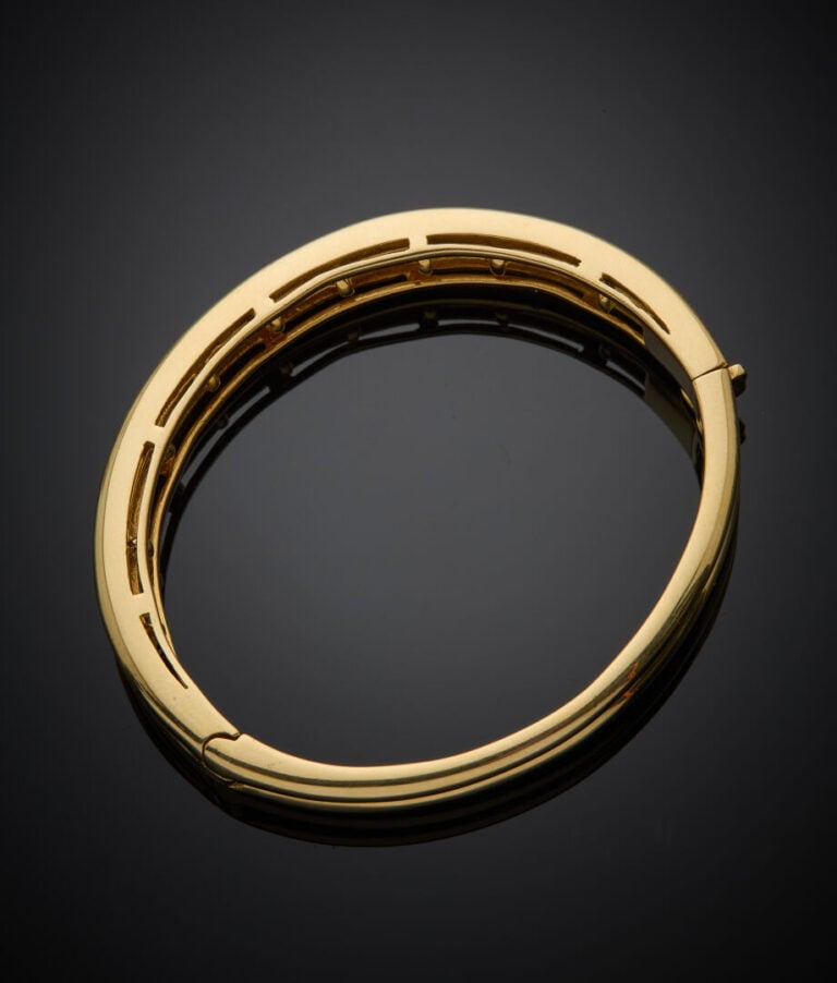 BRACELET rigide ouvrant en or jaune (750‰) eserti d'un alignement de diamants t…
