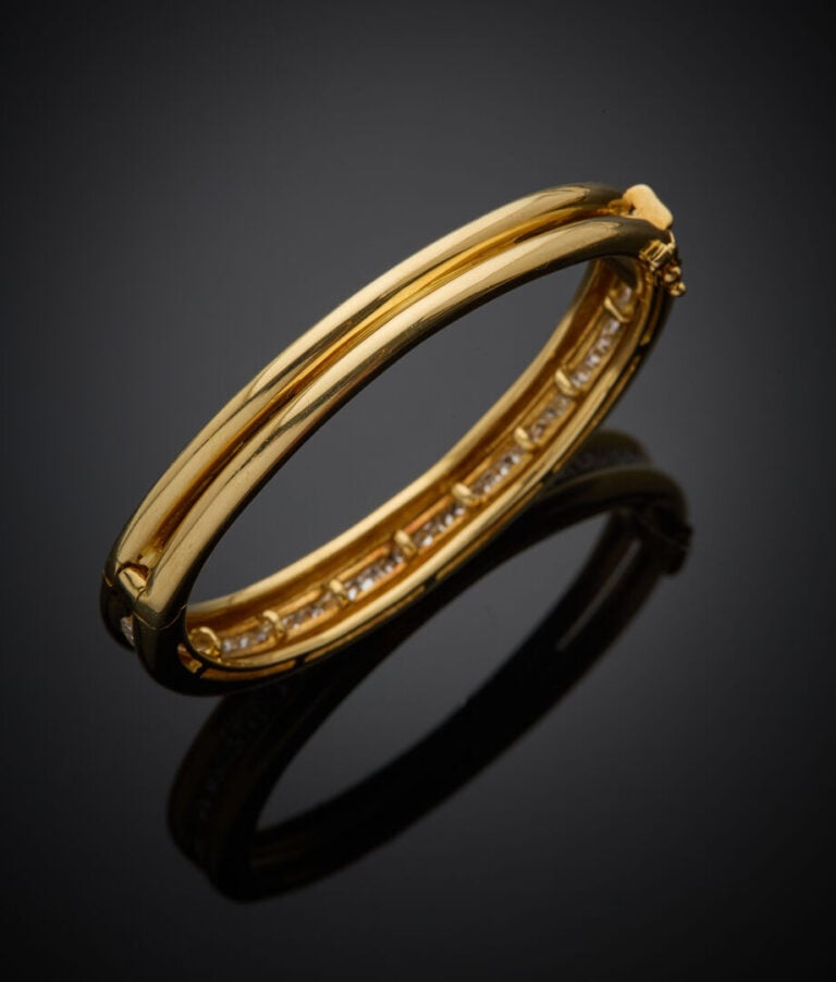 BRACELET rigide ouvrant en or jaune (750‰) eserti d'un alignement de diamants t…