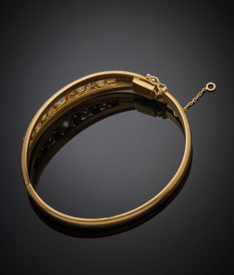 BRACELET rigide ouvrant en or jaune (750‰) godronné, serti d'un alignement de d…