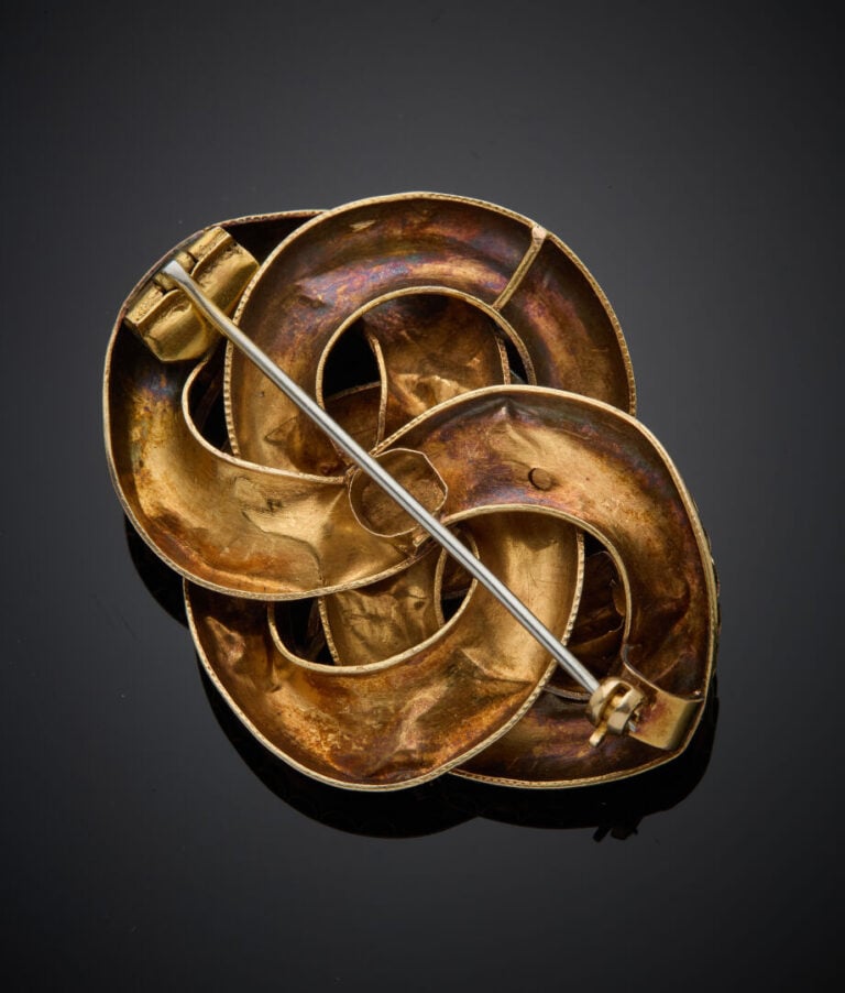 BROCHE "nœud rehaussé de fleurs" en or rose (585‰) 14 carats, ornée d'émeraudes…