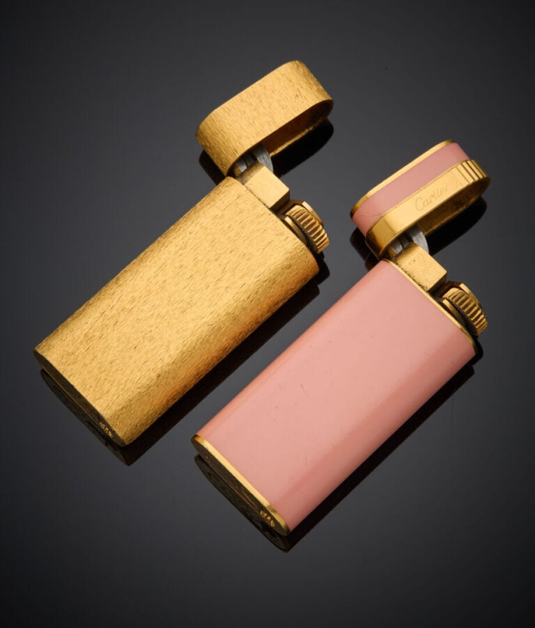 CARTIER - - Deux BRIQUETS en métal doré, l'un orné de laque rose, l'autre entiè…