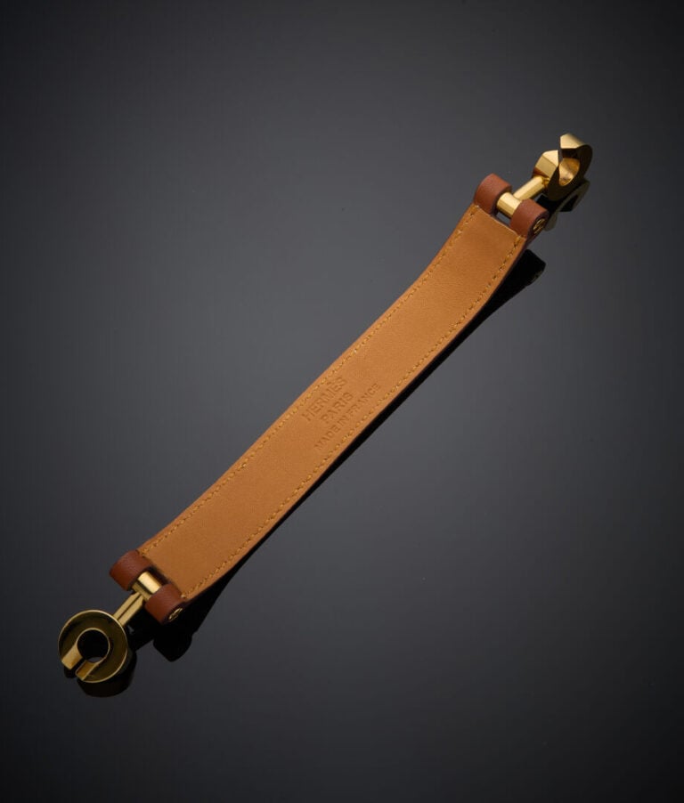 HERMES - - BRACELET "Lancelot" en métal doré, et bracelet cuir. - - Signé HERME…