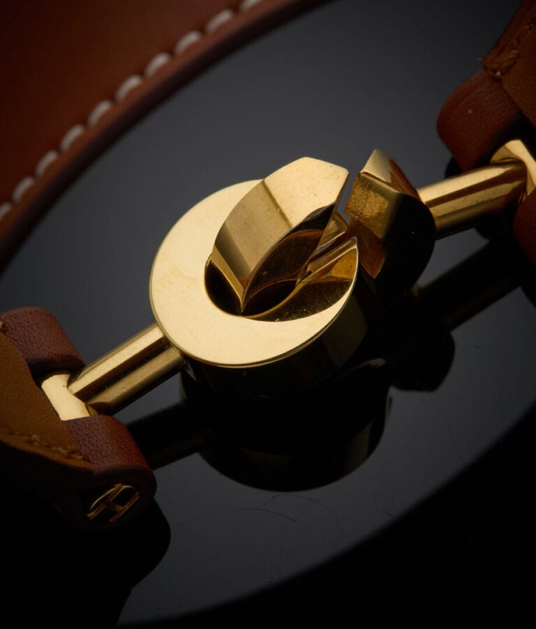 HERMES - - BRACELET "Lancelot" en métal doré, et bracelet cuir. - - Signé HERME…
