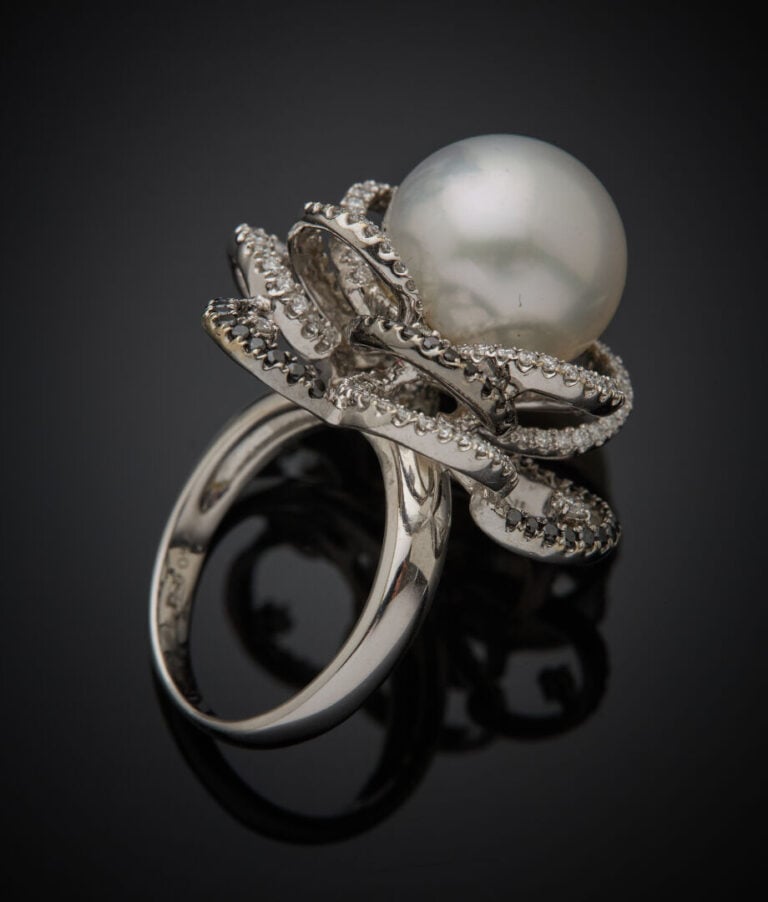 Importante BAGUE "fleur" en or gris et or noirci (750‰) ajouré, centrée d'une p…