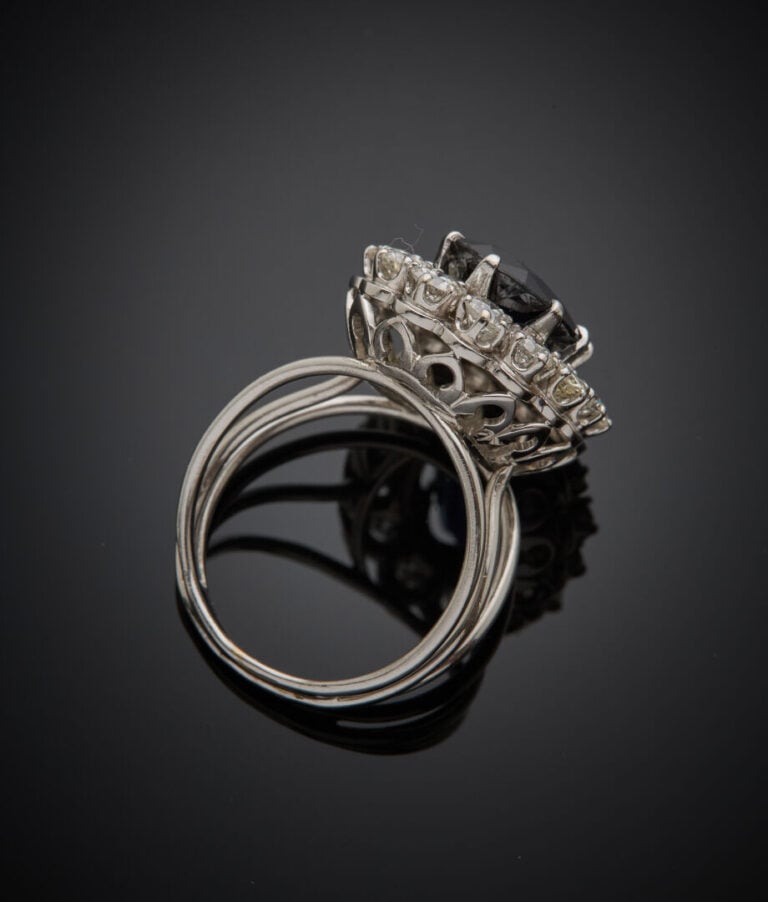 Importante BAGUE « marguerite » en fil d'or gris (750‰) ornée d'un saphir foncé…