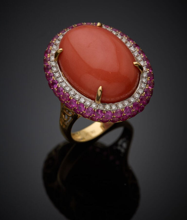 Importante BAGUE ovale en or jaune (750‰) serti d'un corail cabochon, dans un d…