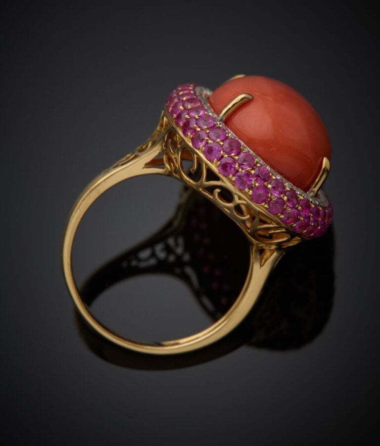 Importante BAGUE ovale en or jaune (750‰) serti d'un corail cabochon, dans un d…