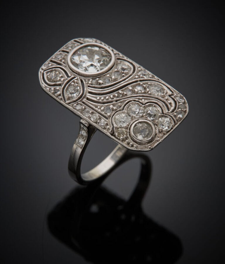 Importante BAGUE "plaque" en platine (950‰) finement ajouré à motifs de volutes…