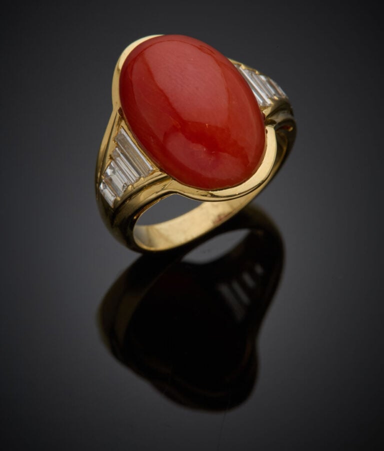 Large BAGUE en or jaune (750‰) ornée d'un corail cabochon, épaulé de huit diama…