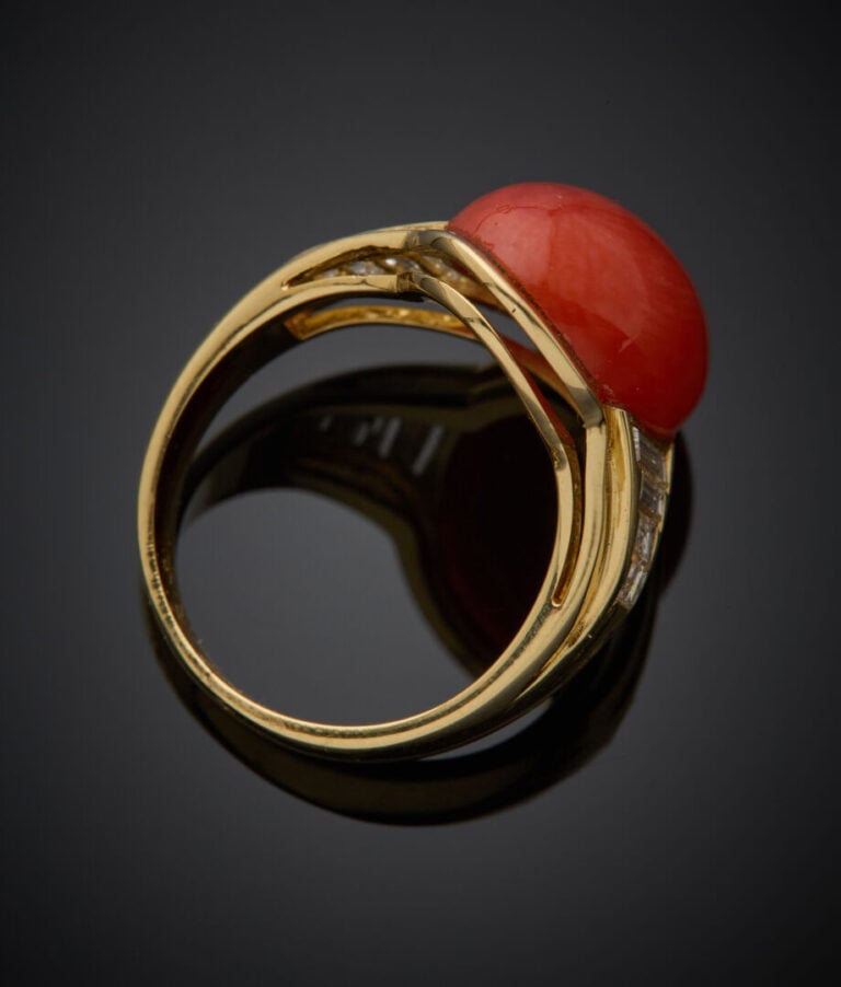 Large BAGUE en or jaune (750‰) ornée d'un corail cabochon, épaulé de huit diama…