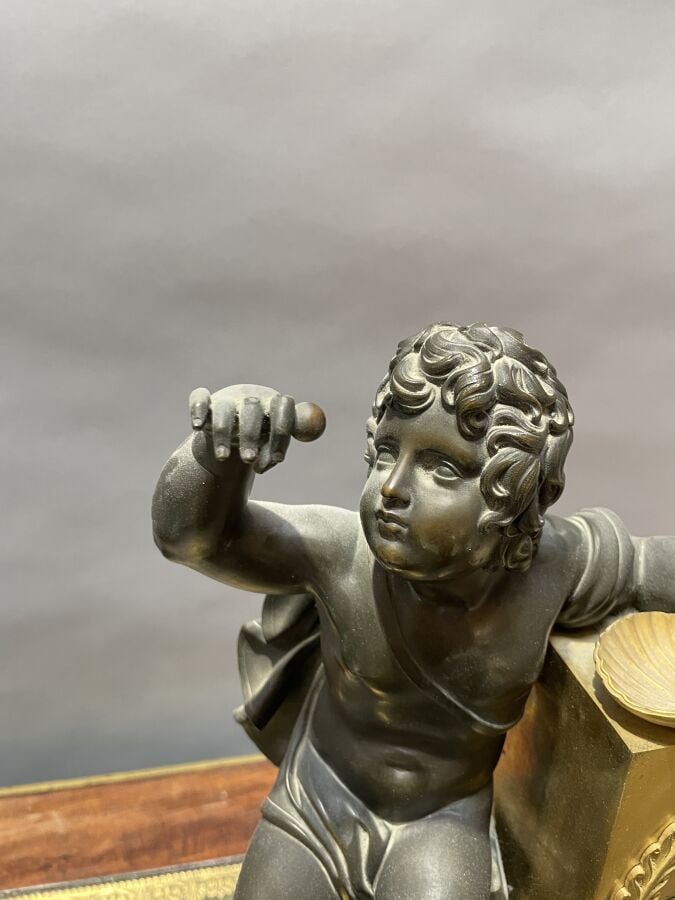 PENDULE BORNE en bronze patiné doré à décor d'un enfant retenant une coquille S…