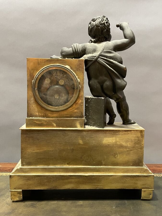 PENDULE BORNE en bronze patiné doré à décor d'un enfant retenant une coquille S…