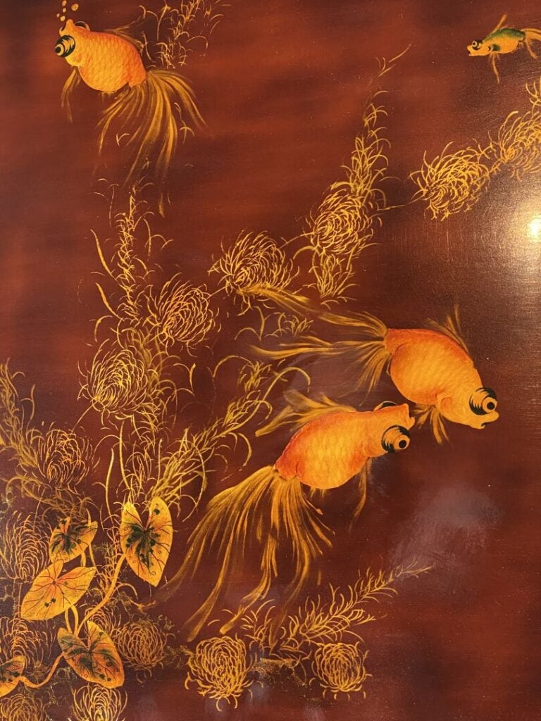 Thanh Le, - Table basse en bois laqué rouge à décor doré de poissons nageant pa…