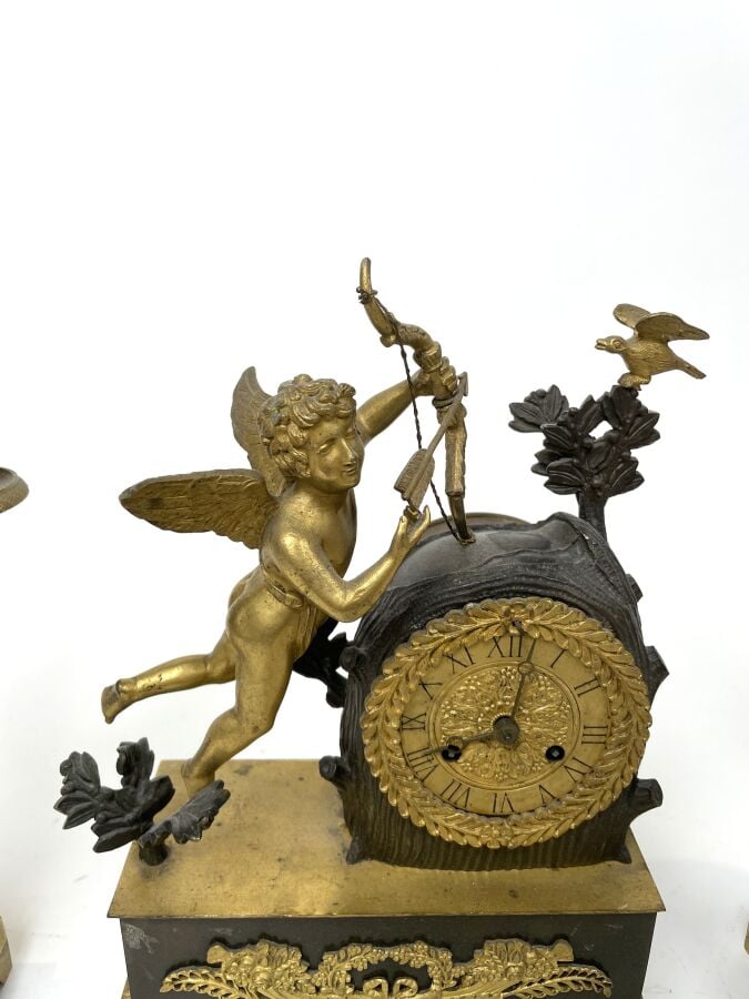 GARNITURE DE CHEMINEE comprenant une pendule à décor en relief d'un amour ailé…