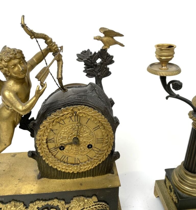 GARNITURE DE CHEMINEE comprenant une pendule à décor en relief d'un amour ailé…