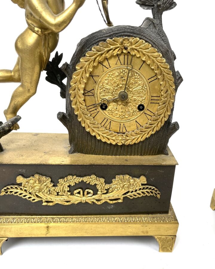 GARNITURE DE CHEMINEE comprenant une pendule à décor en relief d'un amour ailé…