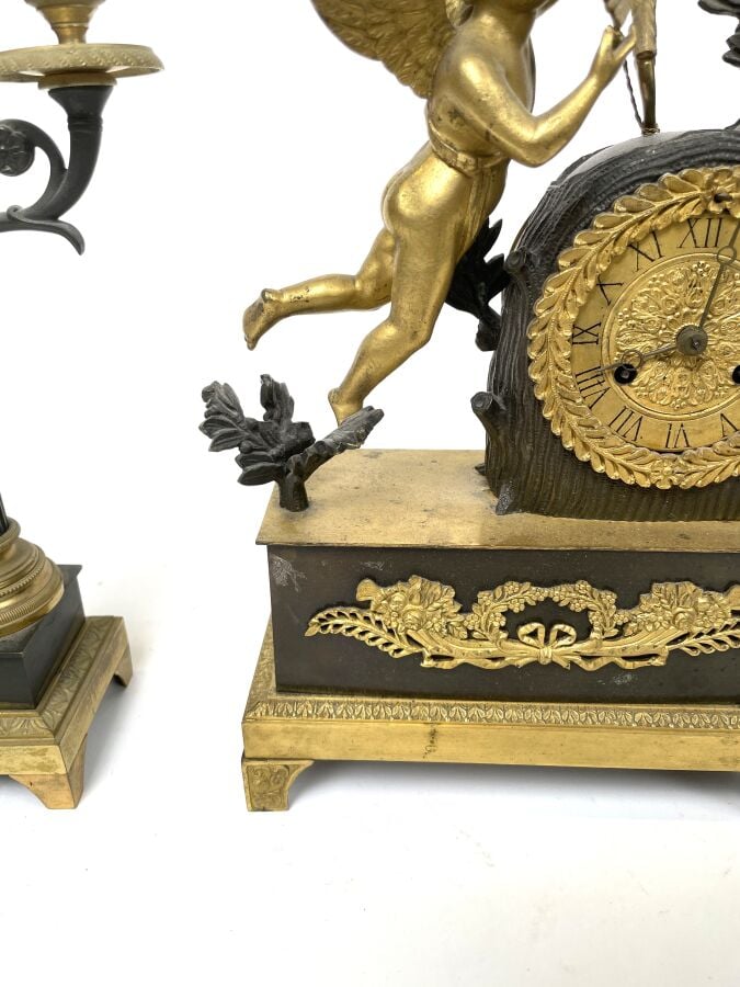GARNITURE DE CHEMINEE comprenant une pendule à décor en relief d'un amour ailé…