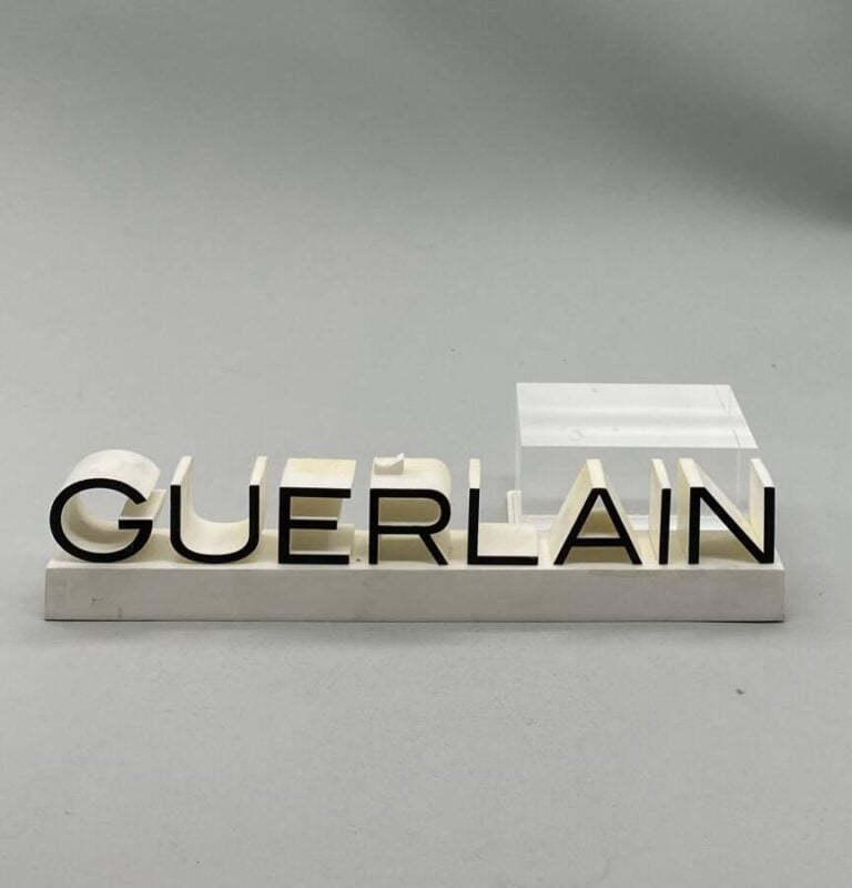 GUERLAIN., Un lot de 3 pièces : - - Un présentoir Guerlain en plastique pour pe…