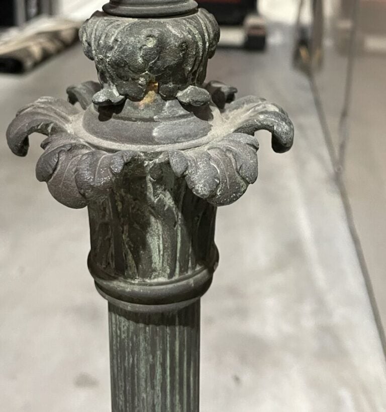 LAMPADAIRE en métal patiné vert, piètement tripode à décor de têtes de boucs te…