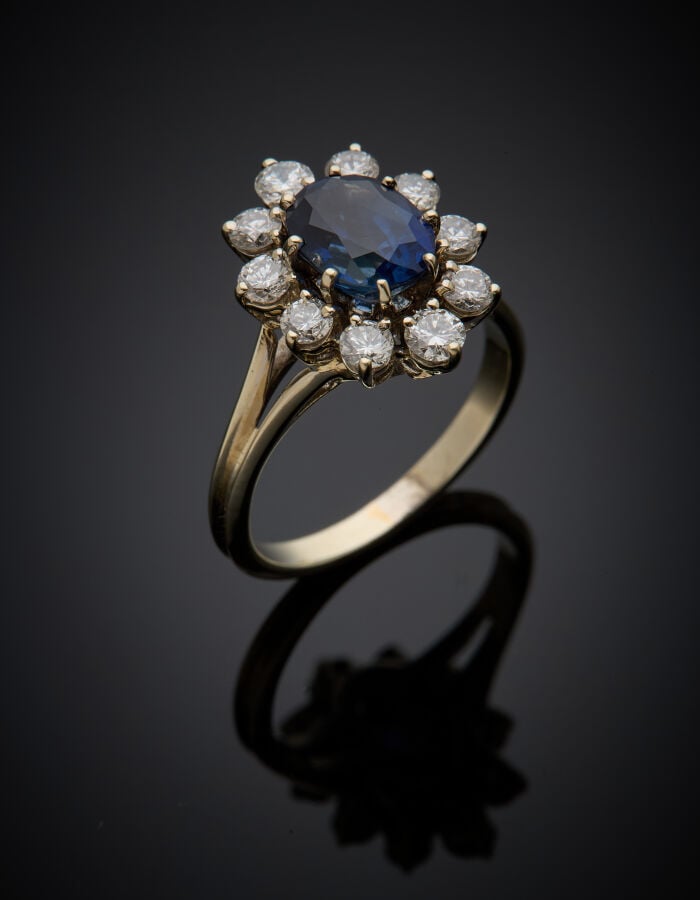 BAGUE "marguerite" en or gris (750‰) serti d'un saphir ovale, entouré de dix di…