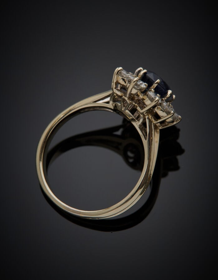 BAGUE "marguerite" en or gris (750‰) serti d'un saphir ovale, entouré de dix di…