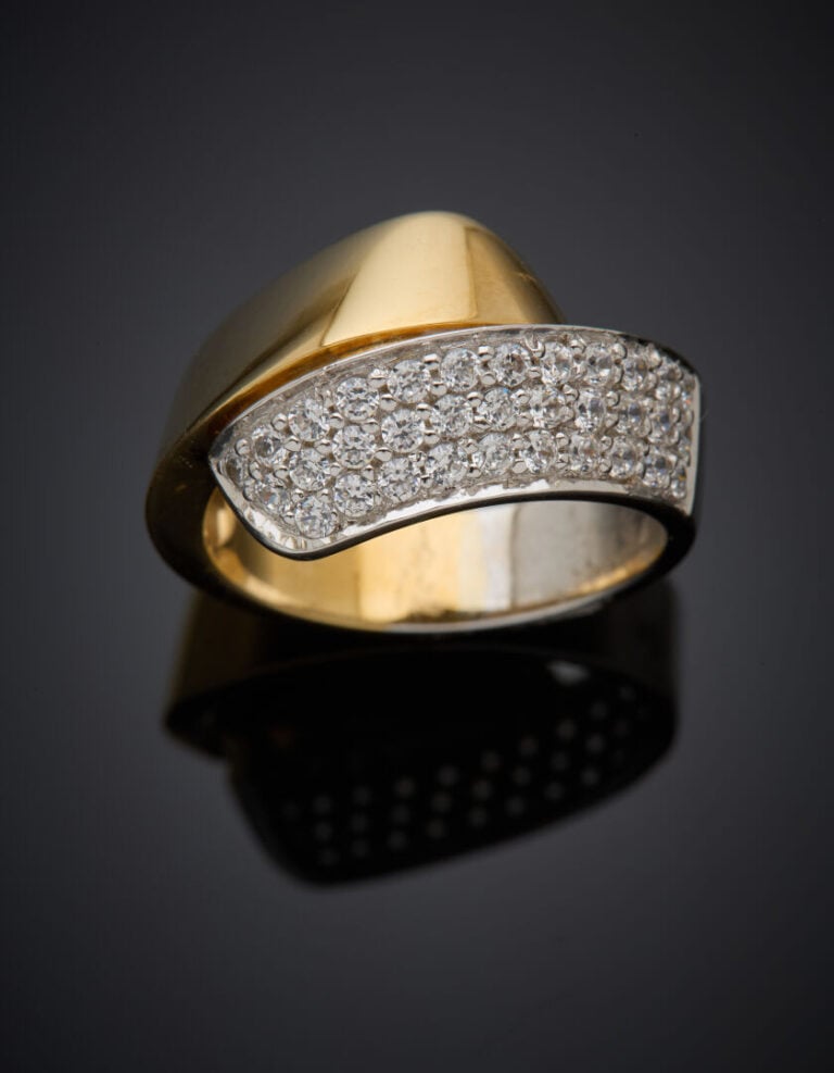 BAGUE "ruban" asymétrique en or jaune et or gris (750°/°°) partiellement pavée…