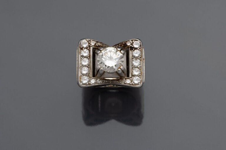 BAGUE "Tank" "nœud stylisé" en platine (min.800):))) ajouré, serti d'un diamant…