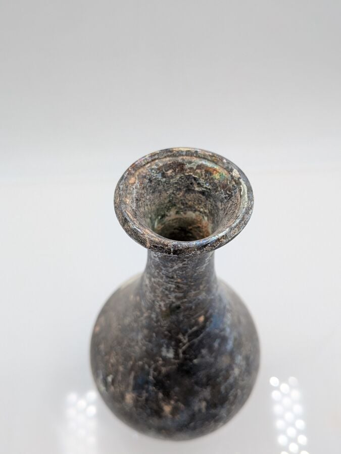 Bouteille à panse piriforme au col concave et pied tronconique. - Verre à épais…