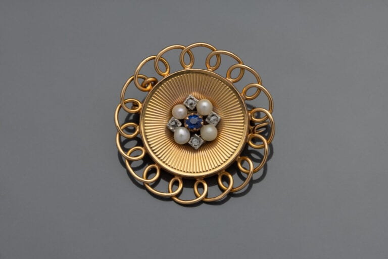 BROCHE fleur en or guilloché centrée d'un saphir, de perles et de diamants tail…