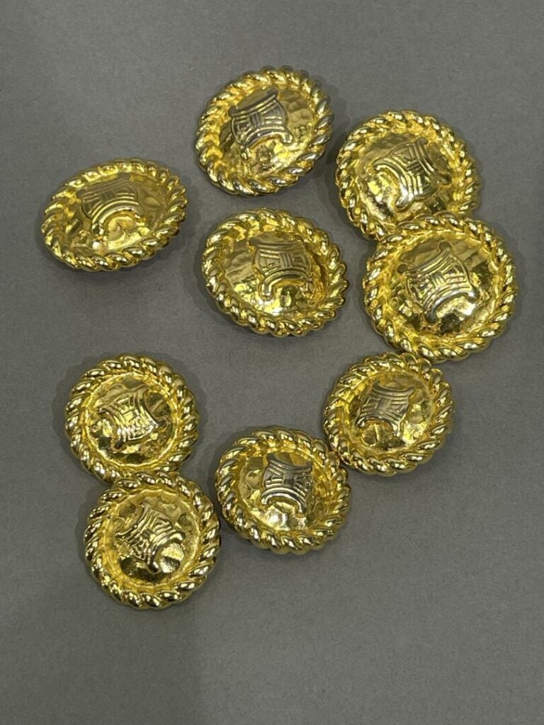 CÉLINE - Lot de neuf boutons bombés en métal doré à effet entrelacé (signés sur…