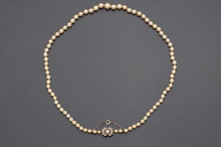 COLLIER de perles de culture. Fermoir formant fleur en or (750°/°°). - Long. 56…