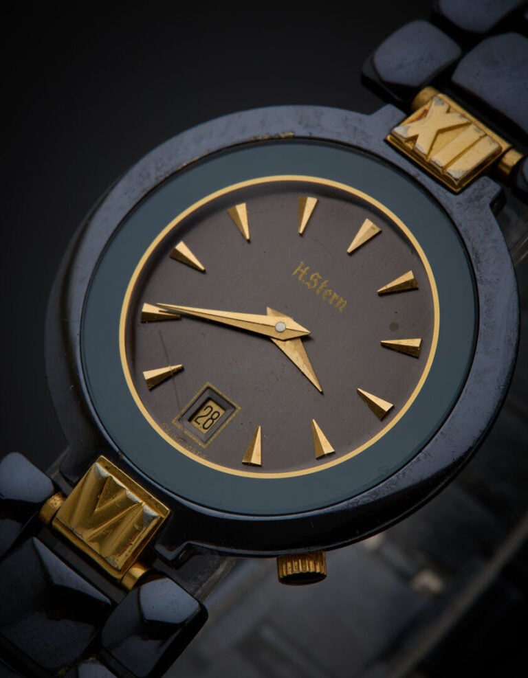 H. STERN - BRACELET MONTRE ronde de dame en acier noirci, attaches dorées. Cadr…