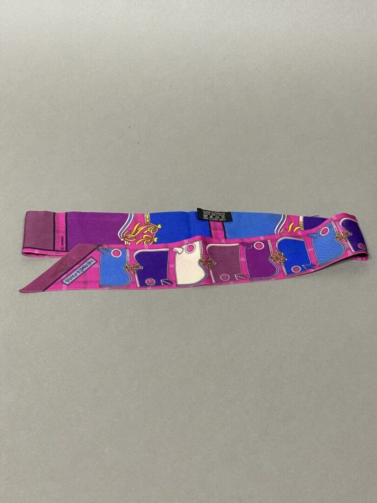 HERMÈS - Twilly « Camails » en soie imprimée fuschia, à décors de camails multi…