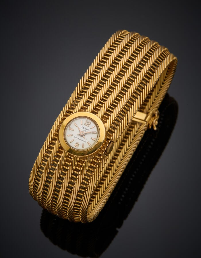 Large BRACELET MONTRE ronde de dame en or jaune (750‰). Cadran crème, index bât…