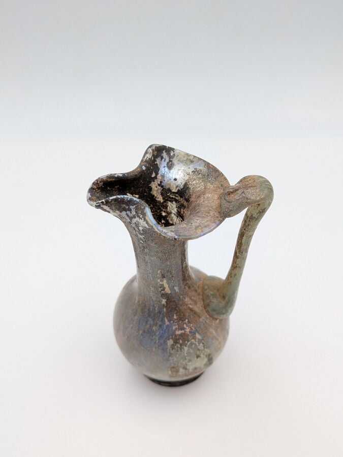 OEnochoé à lèvre pincée, à haut col et pied discoïde. Verre translucide violine…