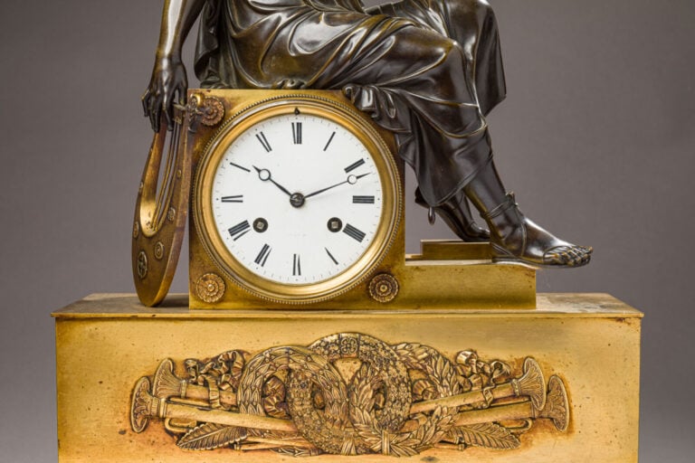Pendule en bronze patiné et doré sommée d'un musicien tenant une Lyre dans sa m…