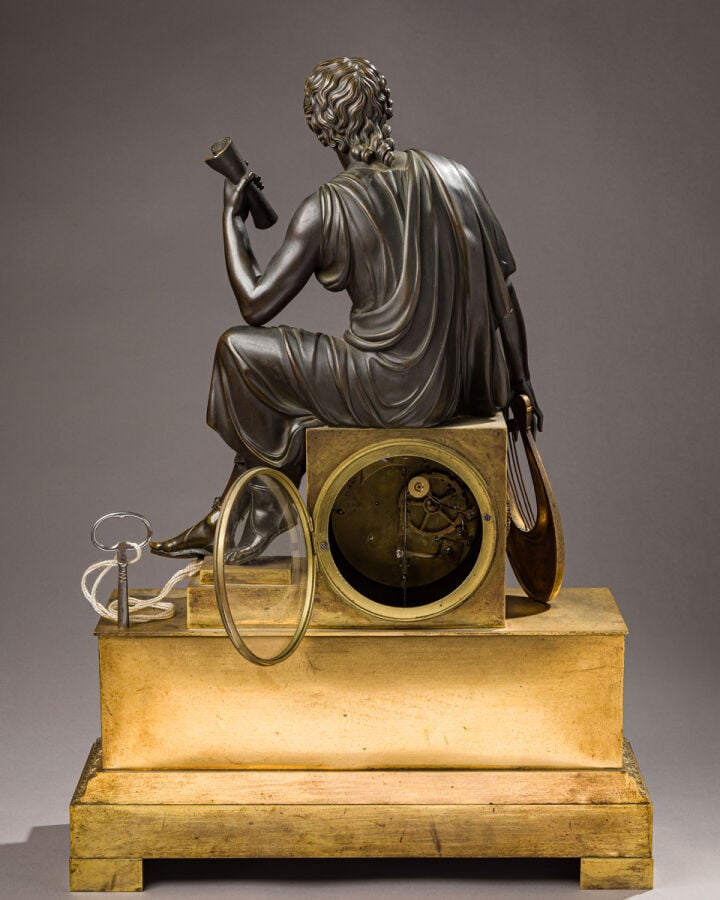 Pendule en bronze patiné et doré sommée d'un musicien tenant une Lyre dans sa m…