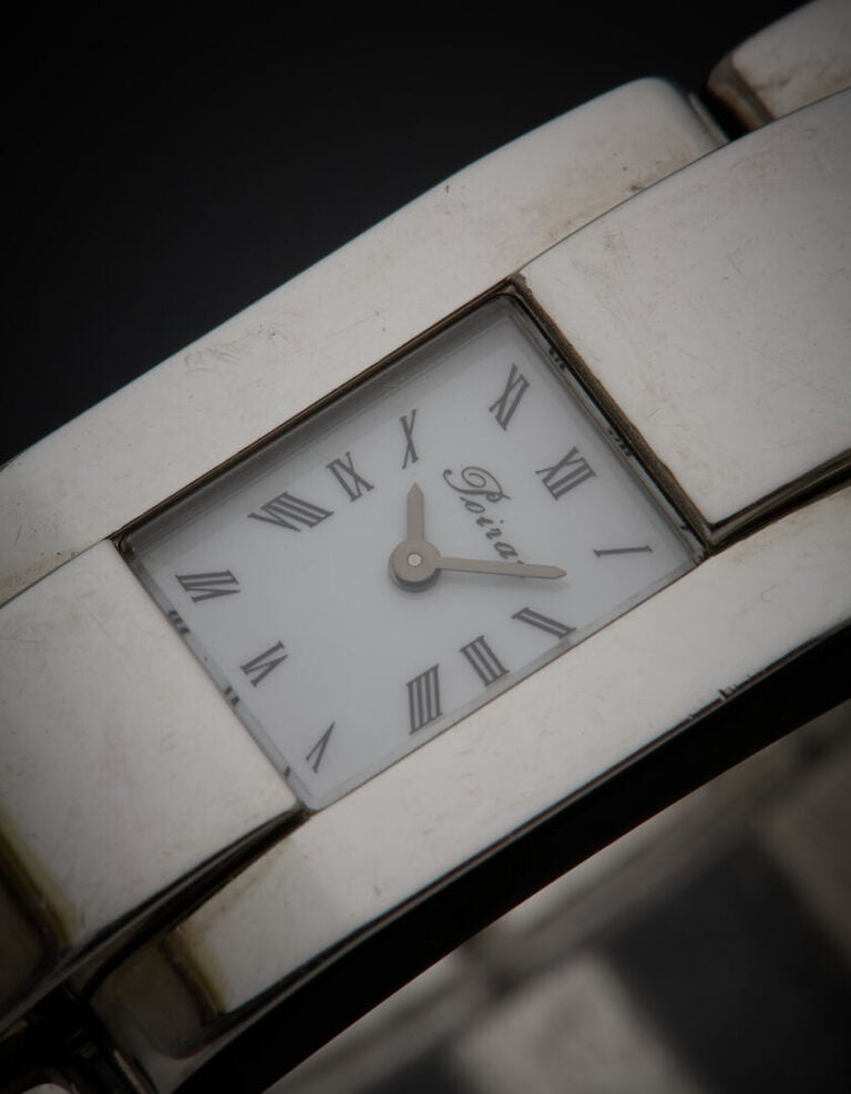 POIRAY - BRACELET MONTRE rectangulaire en acier. Cadran blanc, chiffres romains…