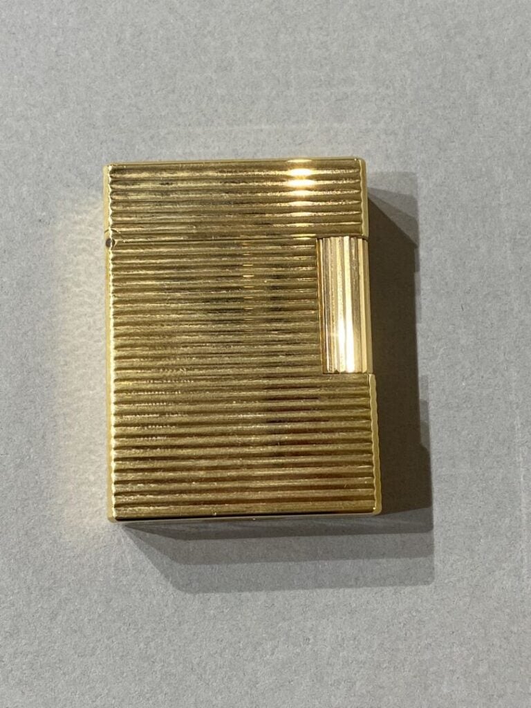 S.T. DUPONT - BRIQUET en métal doré. - Signé S.T. DUPONT. Dans son écrin.