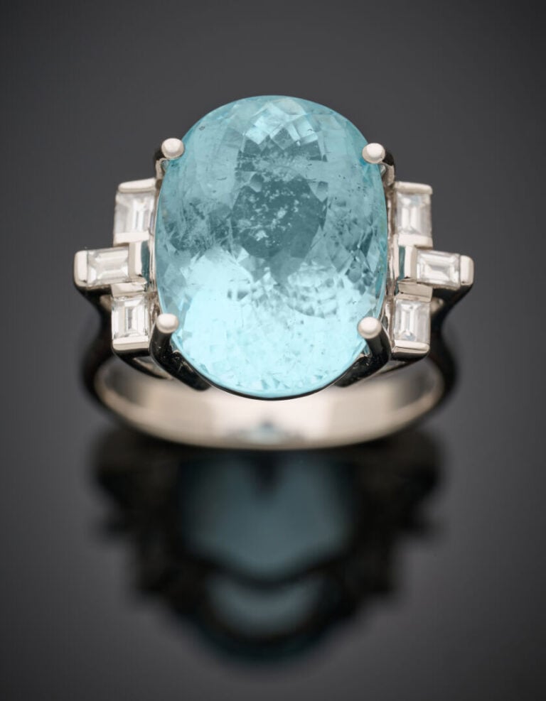 BAGUE en or gris (750‰) serti d'une aigue-marine ovale, épaulée de six diamants…